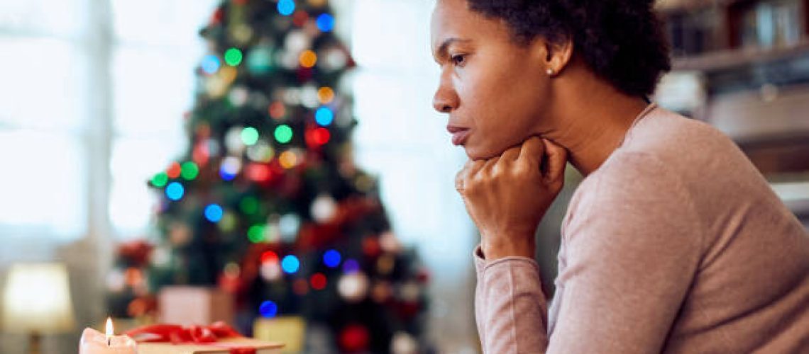 Worried African American woman thinking of something while spending Christmas alone at home.